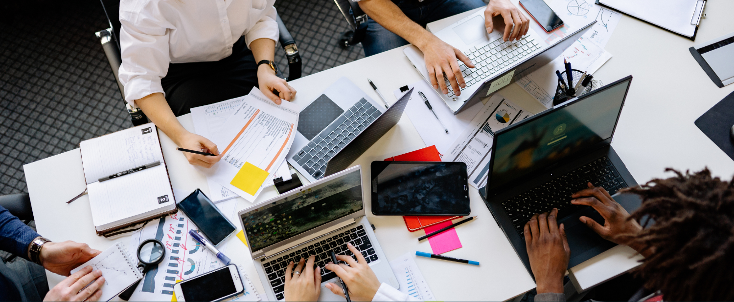 Coworkers sit at a cluttered desk 
